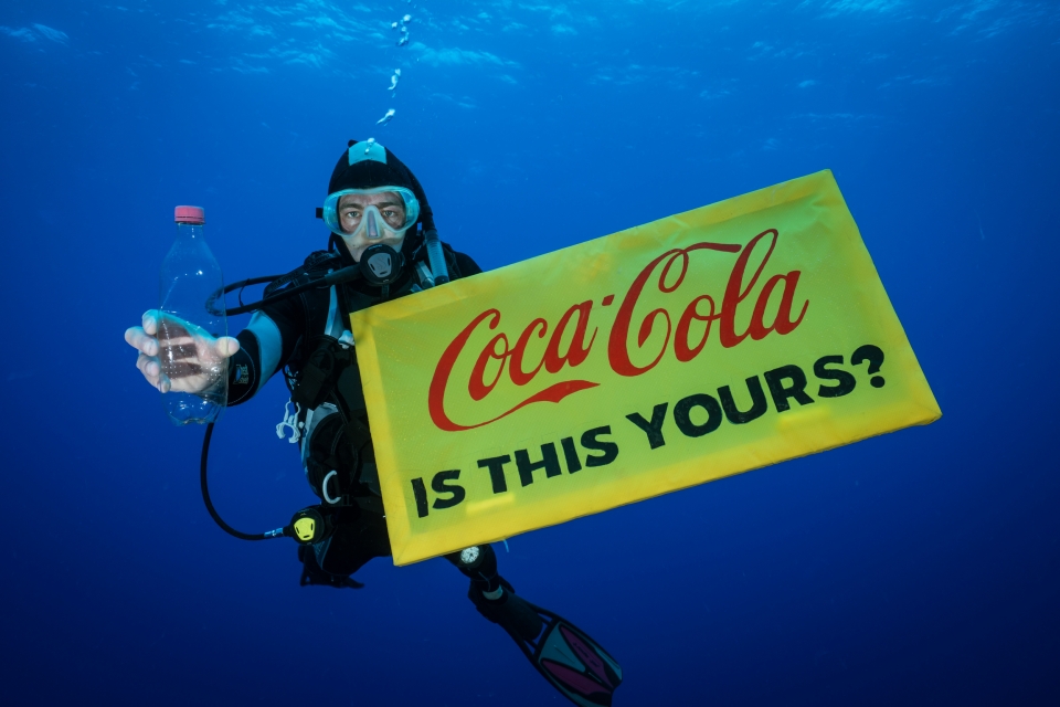 그린피스 활동가가 바다에서 수거한 코카콜라 페트병을 들고 배너를 펼쳐보이고 있다.(한국 그린피스 제공)/그린포스트코리아