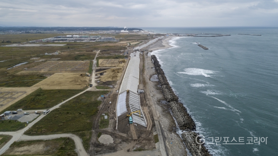 바닷물 유입을 막기 위해 콘크리트 구조물이 태평양 해안을 따라 새로 세워졌다. 멀리 집들이 보이는 마을은 후쿠시마 제1원전에서 북쪽 10km가량 떨어진 나미에 지역이다. 수증기가 나오는 건물은 핵쓰레기 소각공장이다(그린피스 제공)