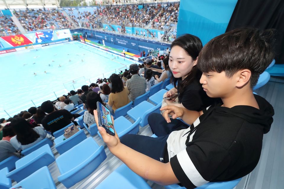 광주세계수영선수권대회 참석한 관람객들이 KT 5G 네트워크를 이용해 핸드폰으로 경기 동영상을 감상하고 있다.(KT 제공) 2019.7.22/그린포스트코리아