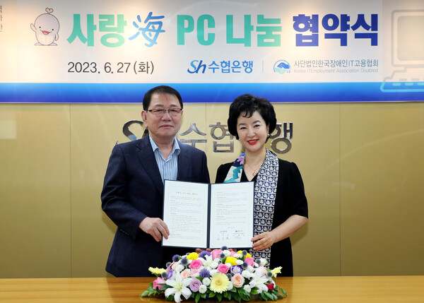 강신숙 수협은행 은행장(오른쪽)과 김용일 한국장애인IT고용협회 대표가 협약서에 서명하고 기념촬영을 하는 모습.(수협은행 제공)/그린포스트코리아