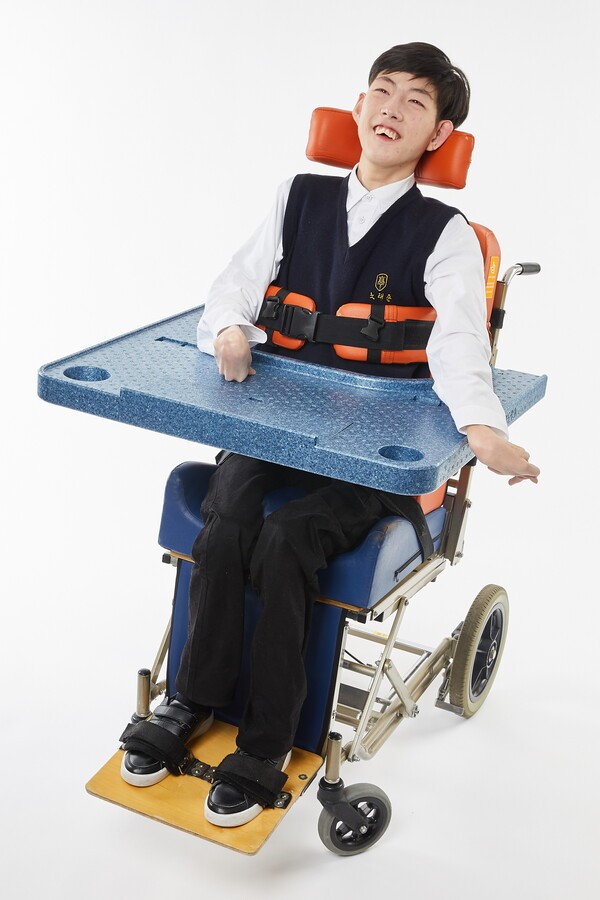뇌병변 장애 자녀를 가진 부모들이 만든 사회적기업 '마마품'이 제작한 초경량 휠체어 테이블. 사진은 최은경 마마품 대표의 자녀가 초경량 휠체어 테이블을 사용하고 있는 모습. /마마품 제공
