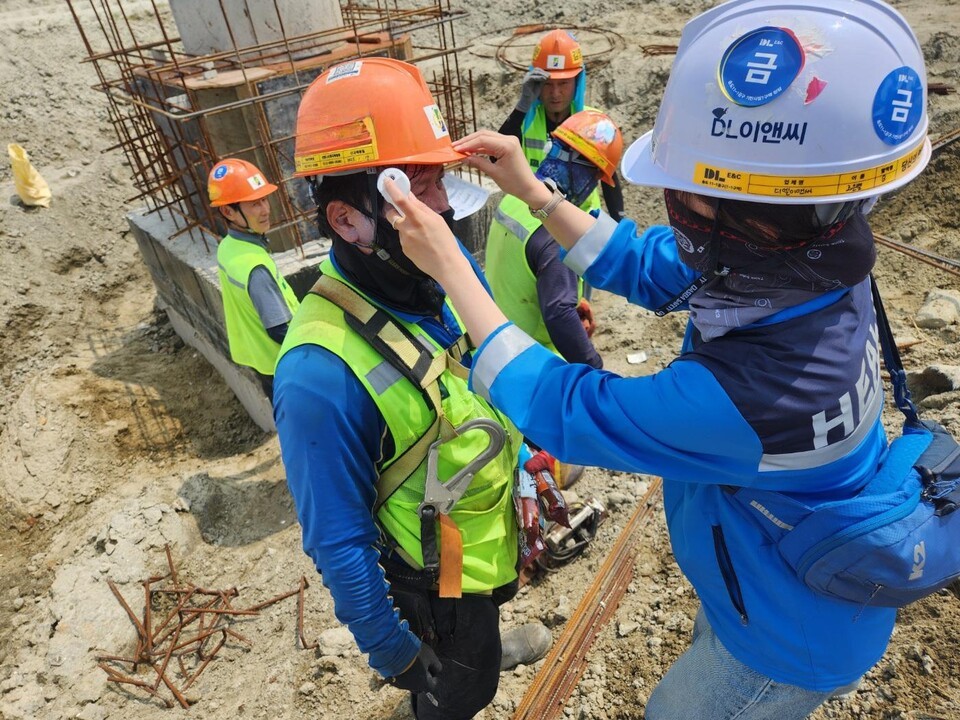 DL이앤씨 현장 안전보건관리자가 근로자의 체온을 측정하고 건강상태를 확인하고 있다./DL이앤씨 제공