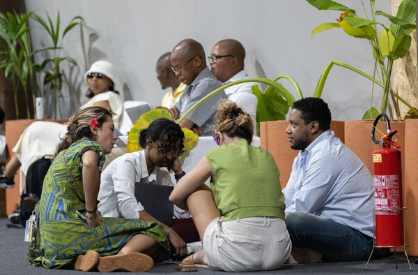 COP30 참가 시민단체 회원들이 지난 22일 새벽 행사장 바닥에 앉아 합의문 도출을  기다리고 있다./UN제공